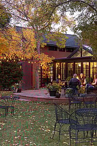 Travelers relax comfortably in the spacious courtyard and visit around the firepit at the Chamberlin Inn, a luxury hotel in Cody Wyoming.