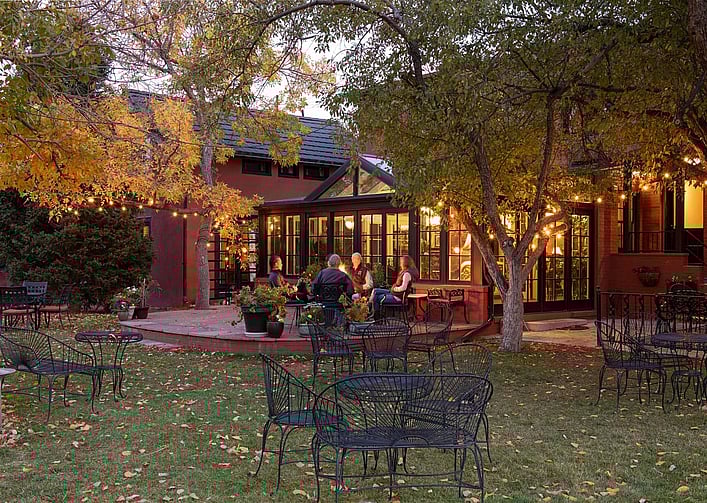 Travelers relax comfortably in the spacious courtyard and visit around the firepit at the Chamberlin Inn, a luxury hotel in Cody Wyoming.