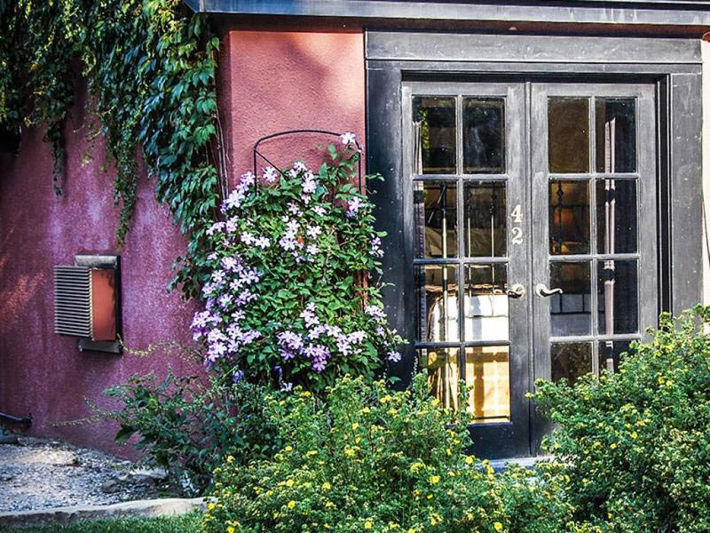 A clematis vine grows next to one of the luxury rooms with access to the courtyard at Cody Wyoming's historic Chamberlin Inn.